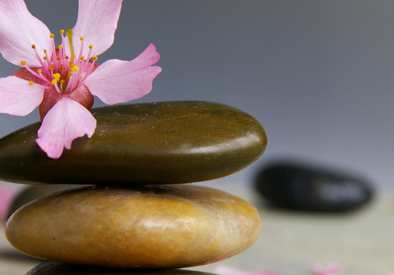 Three colored pebbles placed in order with a flower on top