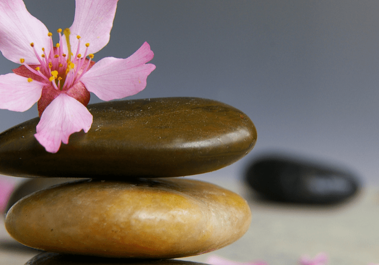 Three colored pebbles placed in order with a flower on top